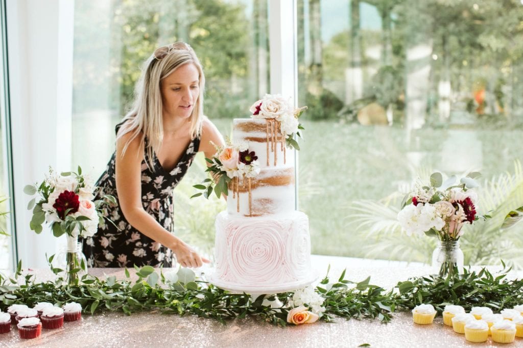 springfield missouri wedding planner allie chaney with allie rose events placing a cake at venue greenhouse two rivers